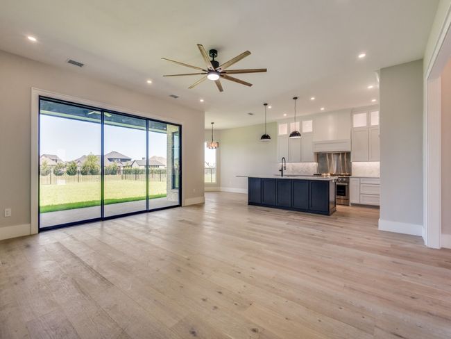 Living room with recessed lighting, baseboards, ceiling fan, light wood-type flooring, kitchen island, Custom Cabinets, Thor professional range-oven, Custom wood surround for ventilation over stove, Stainless backsplash for range | Image 19