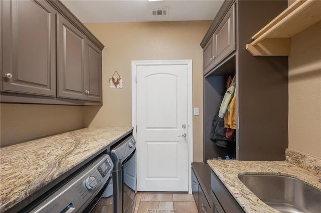 Laundry area featuring cabinet space, independent washer and dryer, and light tile patterned floors | Image 14