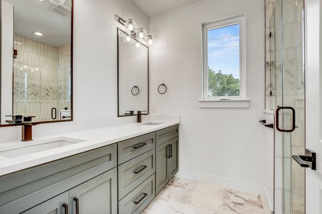 Full bath with marble look tiles, baseboards, double vanity, and a shower stall | Image 4