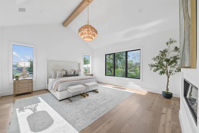 This luxurious primary suite boasts a stunning cathedral ceiling with a striking white oak beam, adding architectural elegance and height to the room. A cozy personal fireplace creates a warm, inviting atmosphere, while the ensuite bath provides a private retreat, completing this serene and sophisticated sanctuary. | Image 37