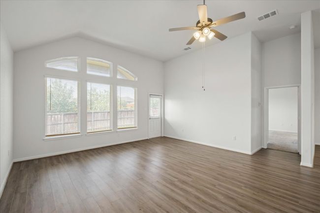 Unfurnished room with ceiling fan, wood finished floors, baseboards, and high vaulted ceiling | Image 6