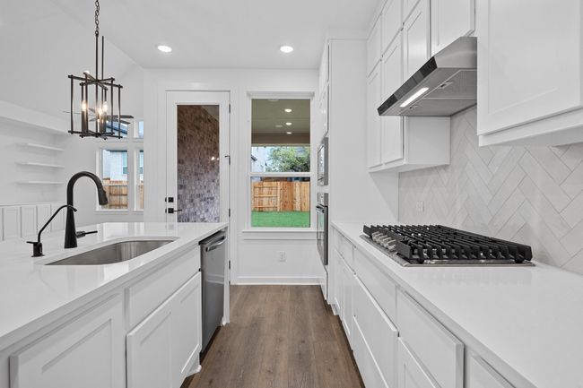 Kitchen featuring wall chimney exhaust hood, stainless steel appliances, white cabinets, light countertops, and recessed lighting | Image 4