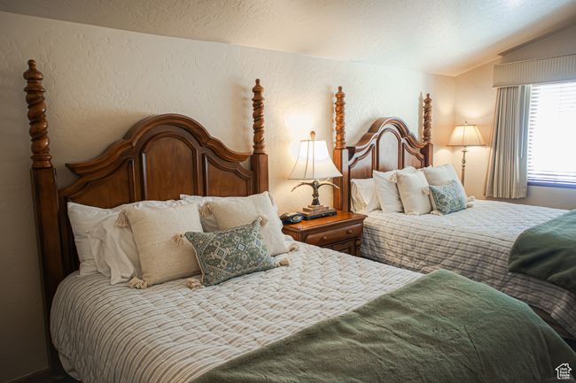 Bedroom featuring vaulted ceiling, a textured wall, and a textured ceiling | Image 21