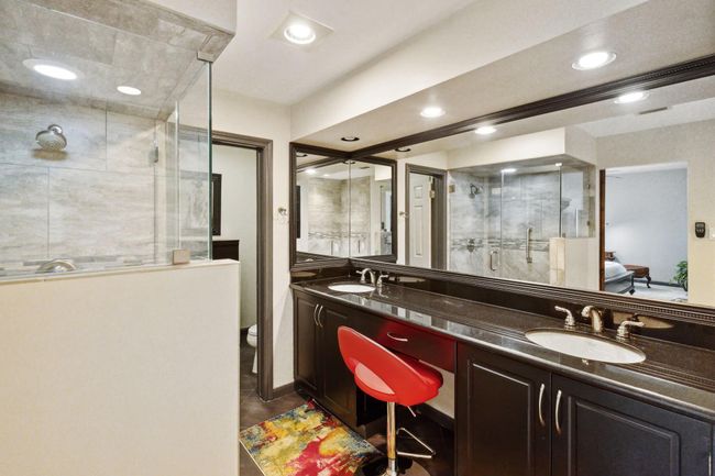 Primary bathroom is accented with stone tile walls and flooring, offering a luxurious feel. | Image 26