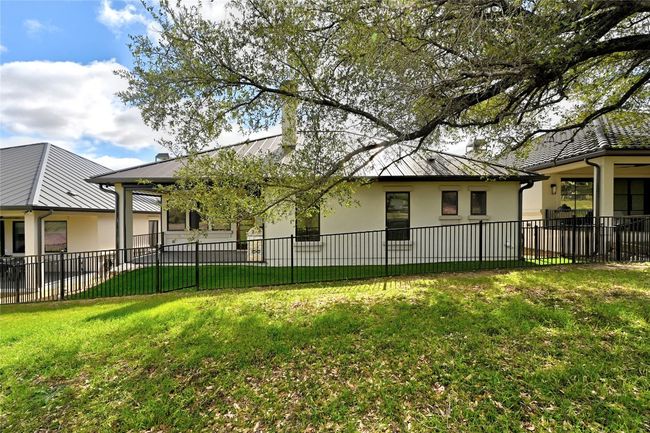 Rear view of property with a lawn, metal roof, fence, and stucco siding | Image 36