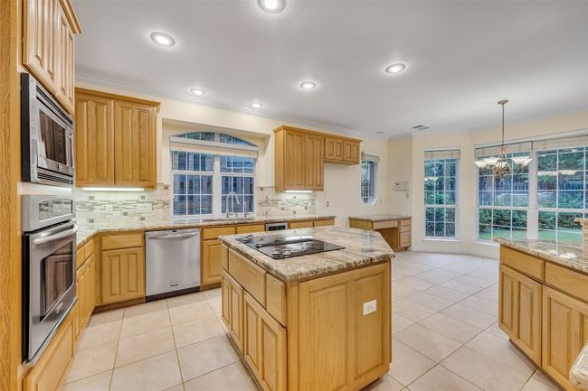 Kitchen featuring appliances with stainless steel finishes, a chandelier, tasteful backsplash, crown molding, and light stone counters | Image 19