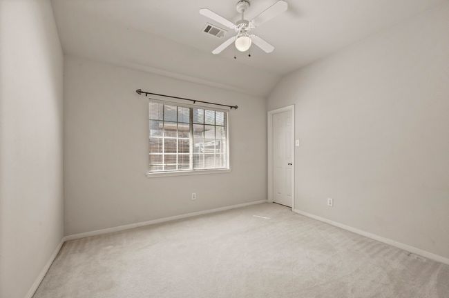 Spare room featuring vaulted ceiling, carpet, baseboards, ceiling fan, and visible vents | Image 31