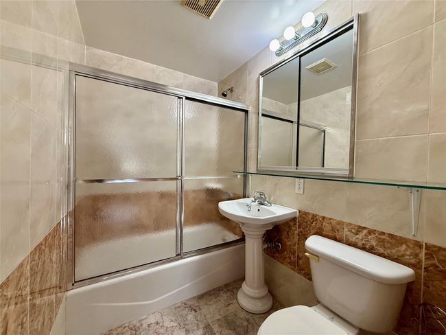 Bathroom with tile walls and enclosed tub / shower combo | Image 4