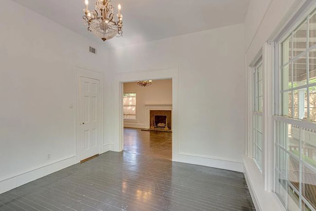 Empty room with a chandelier, plenty of natural light, dark wood-type flooring, and a fireplace with raised hearth | Image 5