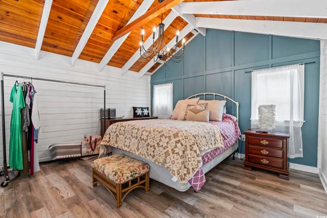 Bedroom featuring a chandelier, wood finished floors, a decorative wall, and wood ceiling | Image 32
