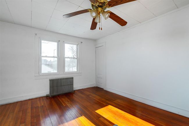 Empty room featuring ceiling fan, dark hardwood / wood-style flooring, radiator heating unit, and crown molding | Image 12