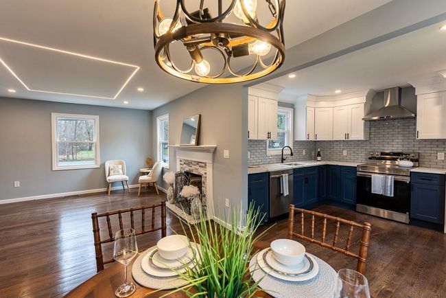 Kitchen with wall chimney range hood, stainless steel appliances, white cabinets, and blue cabinetry | Image 36