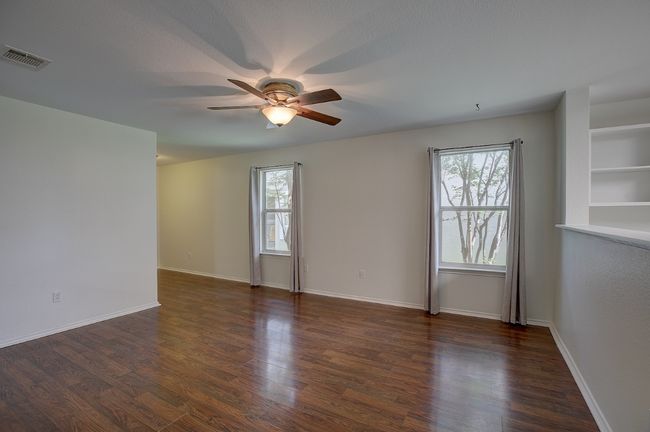 Great light in the open concept family room with a ceiling fan, healthy amount of natural light, and wood finished floors | Image 14