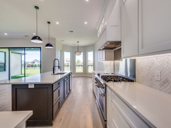 Kitchen featuring stainless steel appliances, a sink, light wood-style floors, decorative backsplash, and recessed lighting | Image 26