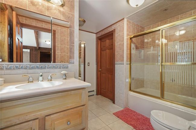 Full bathroom with vanity, enclosed tub / shower combo, toilet, and tile walls | Image 20