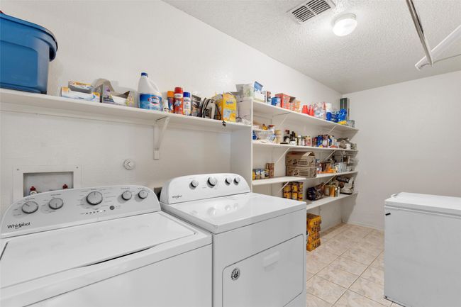 Washroom with washing machine and clothes dryer, a textured ceiling, and light tile patterned flooring | Image 16
