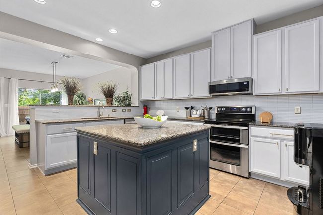 Kitchen with stainless steel appliances, a sink, a center island, light tile patterned floors, and recessed lighting | Image 10
