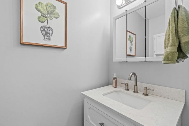 Updated main-level half bath with stylish vanity, new faucet, and framed mirror. | Image 12