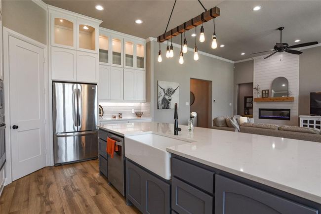 Kitchen with appliances with stainless steel finishes, white cabinetry, a fireplace, and crown molding | Image 7