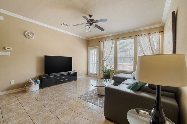 Living area featuring ceiling fan, baseboards, visible vents, light tile patterned flooring, and crown molding | Image 21
