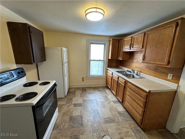 Kitchen with electric stove, sink, and white fridge | Image 5