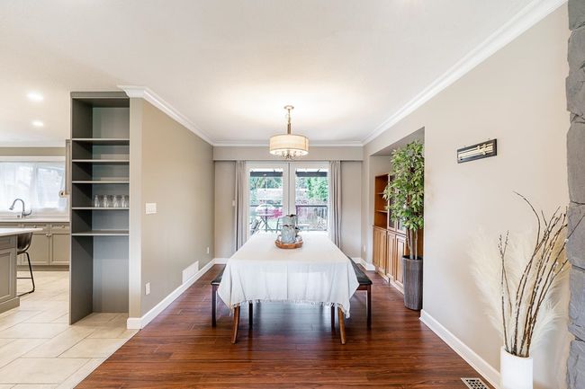 Dining room with light wood-style floors, ornamental molding, baseboards, and visible vents | Image 14