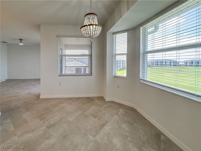 Empty room featuring a chandelier, a ceiling fan, baseboards, and light tile patterned floors | Image 5
