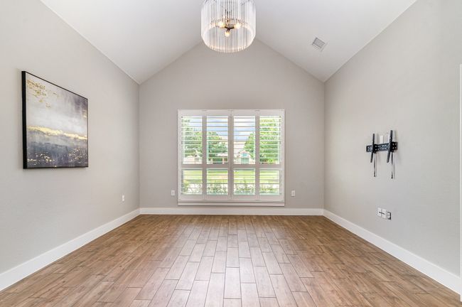 Primary bedroom featuring a chandelier, wood finished floors, baseboards, and vaulted ceiling | Image 17