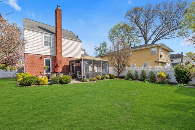 Rear view of house with a chimney, a sunroom, a yard, and a fenced backyard | Image 17