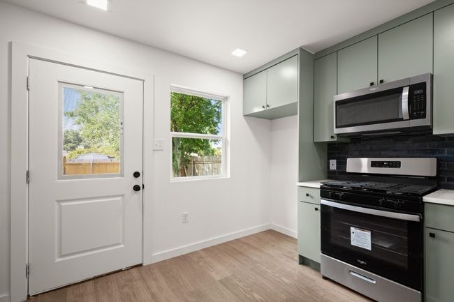 Kitchen featuring stainless steel appliances, light countertops, tasteful backsplash, light wood-style floors, and gray cabinets | Image 11