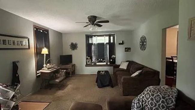 Carpeted living room featuring a textured ceiling and ceiling fan | Image 6
