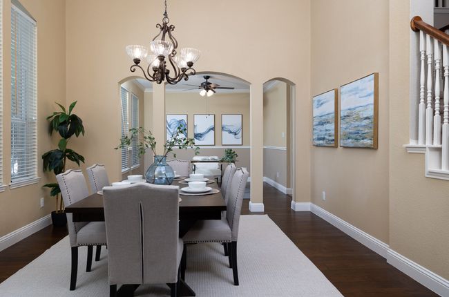 Dining room with arched walkways, dark wood finished floors, ceiling fan, a towering ceiling, and a chandelier | Image 6
