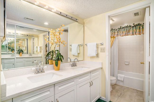 Primary en-suite bathroom features quartz countertops, newer cabinetry, double sinks, dressing area and private bathtub/shower and comfort station. | Image 13