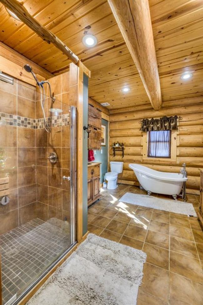 Full bath with tile patterned floors, rustic walls, wood ceiling, and a shower stall | Image 23