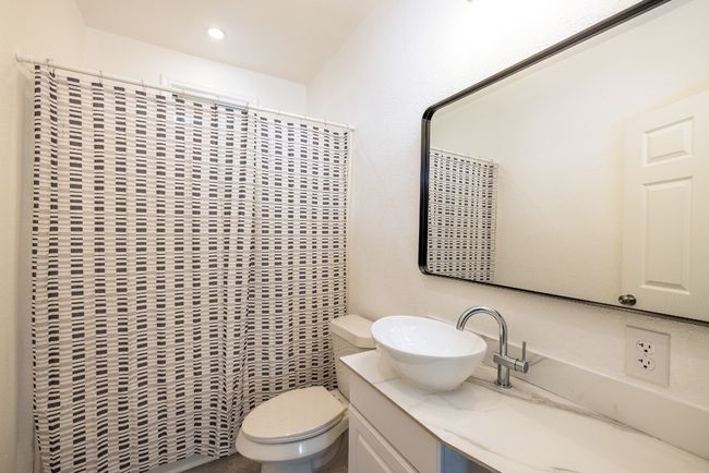 Bathroom with toilet, curtained shower, vanity, and recessed lighting | Image 20