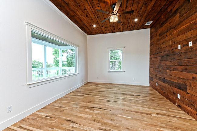 Living Room room with wood ceiling, a ceiling fan, wood finished floors, ornamental molding, and wooden walls | Image 10