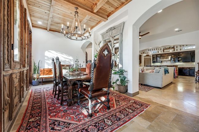 Dining space featuring visible vents, beamed ceiling, wood ceiling, ceiling fan with notable chandelier, and arched walkways | Image 8