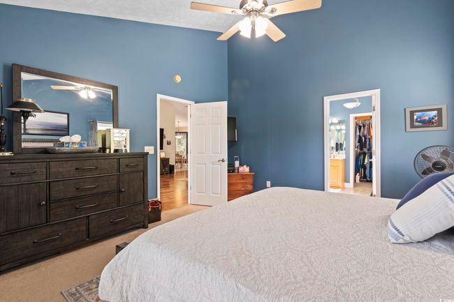 Carpeted bedroom with high vaulted ceiling, a spacious closet, and a ceiling fan | Image 19