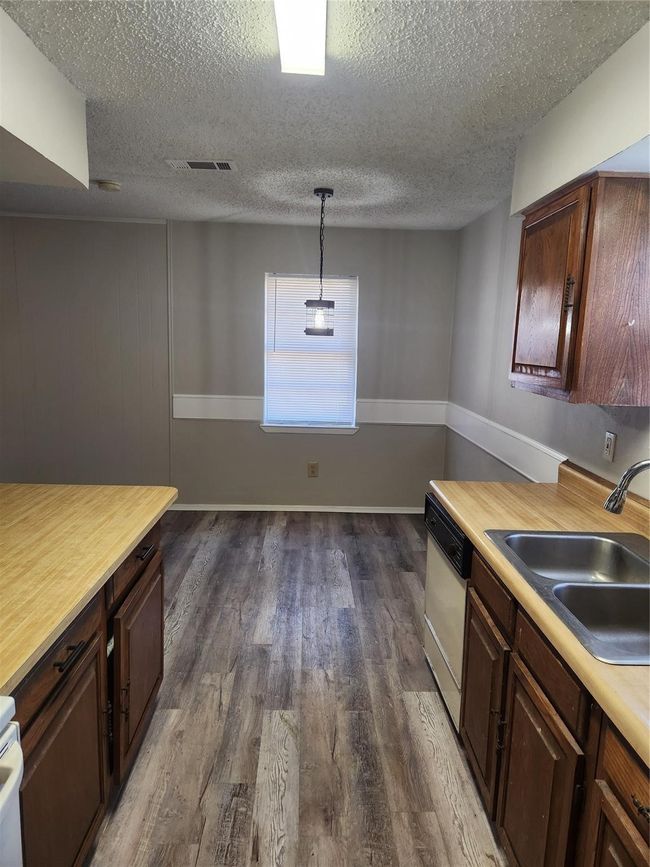 Kitchen with dishwasher, a sink, light countertops, dark wood-style flooring, and a textured ceiling | Image 11