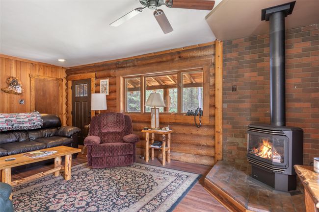 Living area featuring a wood stove, a ceiling fan, wood finished floors, and log walls | Image 32