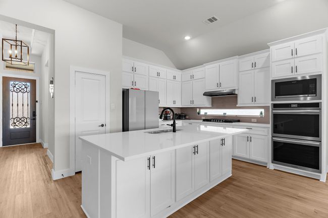 Kitchen featuring stainless steel appliances, a sink, vaulted ceiling, white cabinets, and recessed lighting | Image 8
