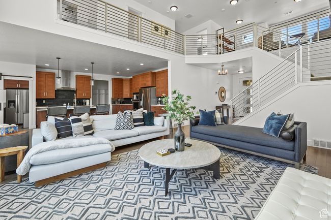 Living room featuring a towering ceiling, wood finished floors, stairs, and recessed lighting | Image 11
