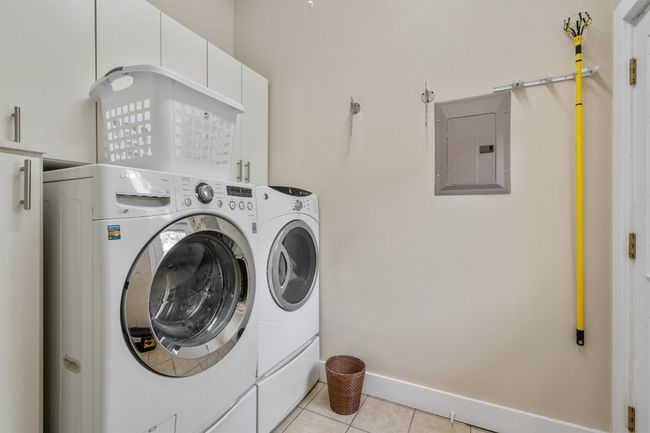 Laundry room with electric panel, washer and clothes dryer, light tile patterned flooring, and baseboards | Image 23