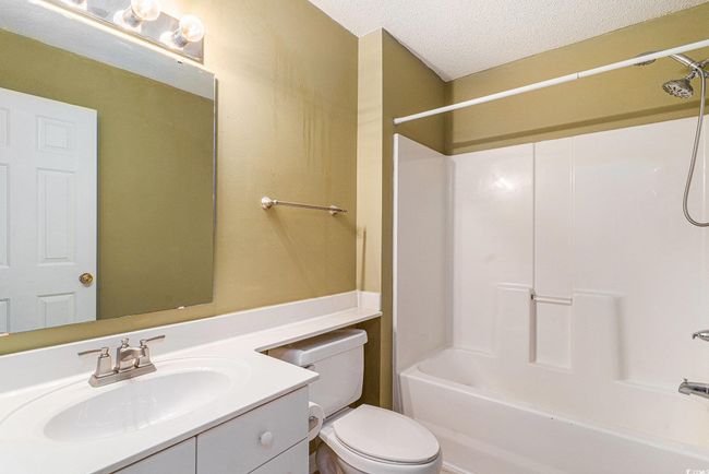 Full bath featuring vanity, toilet, a textured ceiling, and washtub / shower combination | Image 8