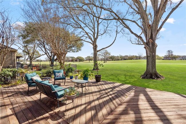 This backyard deck provides a seamless connection to the golf course, offering an expansive and peaceful outdoor retreat. The well-maintained wooden deck is complemented by lush greenery, mature trees, and open views, creating an ideal setting for relaxation or entertaining. The natural surroundings enhance the serene ambiance, making this space a perfect spot to unwind. | Image 34