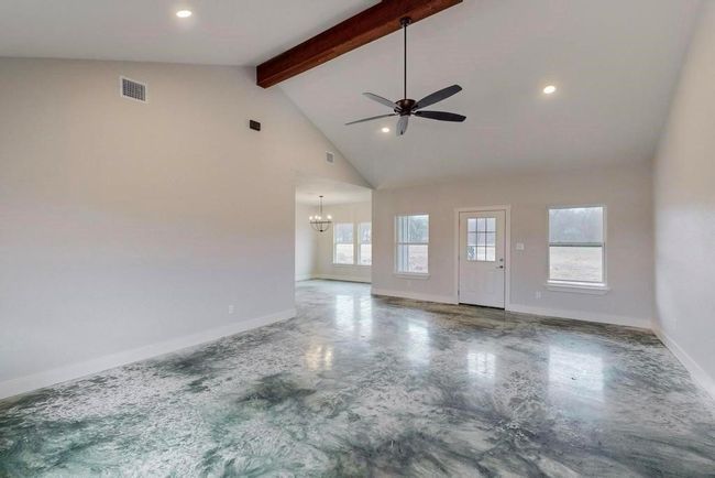 Unfurnished living room with ceiling fan with notable chandelier, beamed ceiling, high vaulted ceiling, visible vents, and​​‌​​​​‌​​‌‌​‌‌​​​‌‌​​‌‌​‌​​​​​‌ baseboards | Image 6