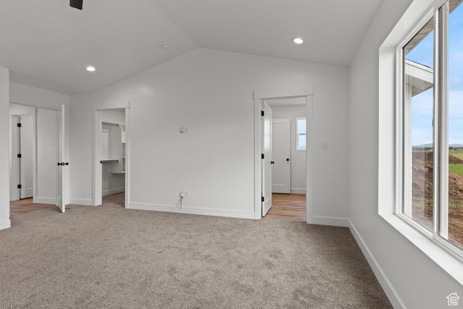 Unfurnished bedroom featuring multiple windows, carpet floors, baseboards, lofted ceiling, and a walk in closet | Image 11
