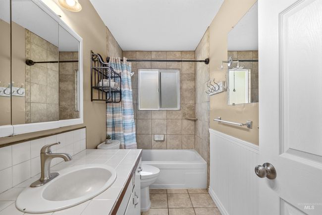 Full bath featuring shower / bath combination with curtain, tile patterned floors, and vanity | Image 16