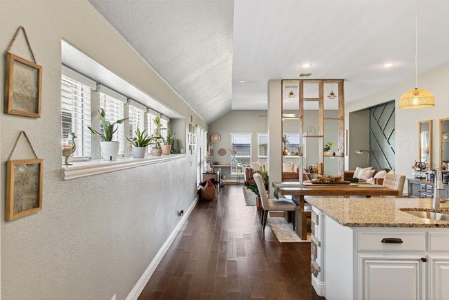 Kitchen with light stone counters, white cabinets, dark wood-style floors, decorative light fixtures, and a textured wall | Image 10