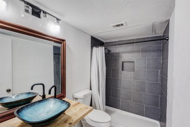 Full bath with a shower stall, toilet, visible vents, and a sink | Image 5
